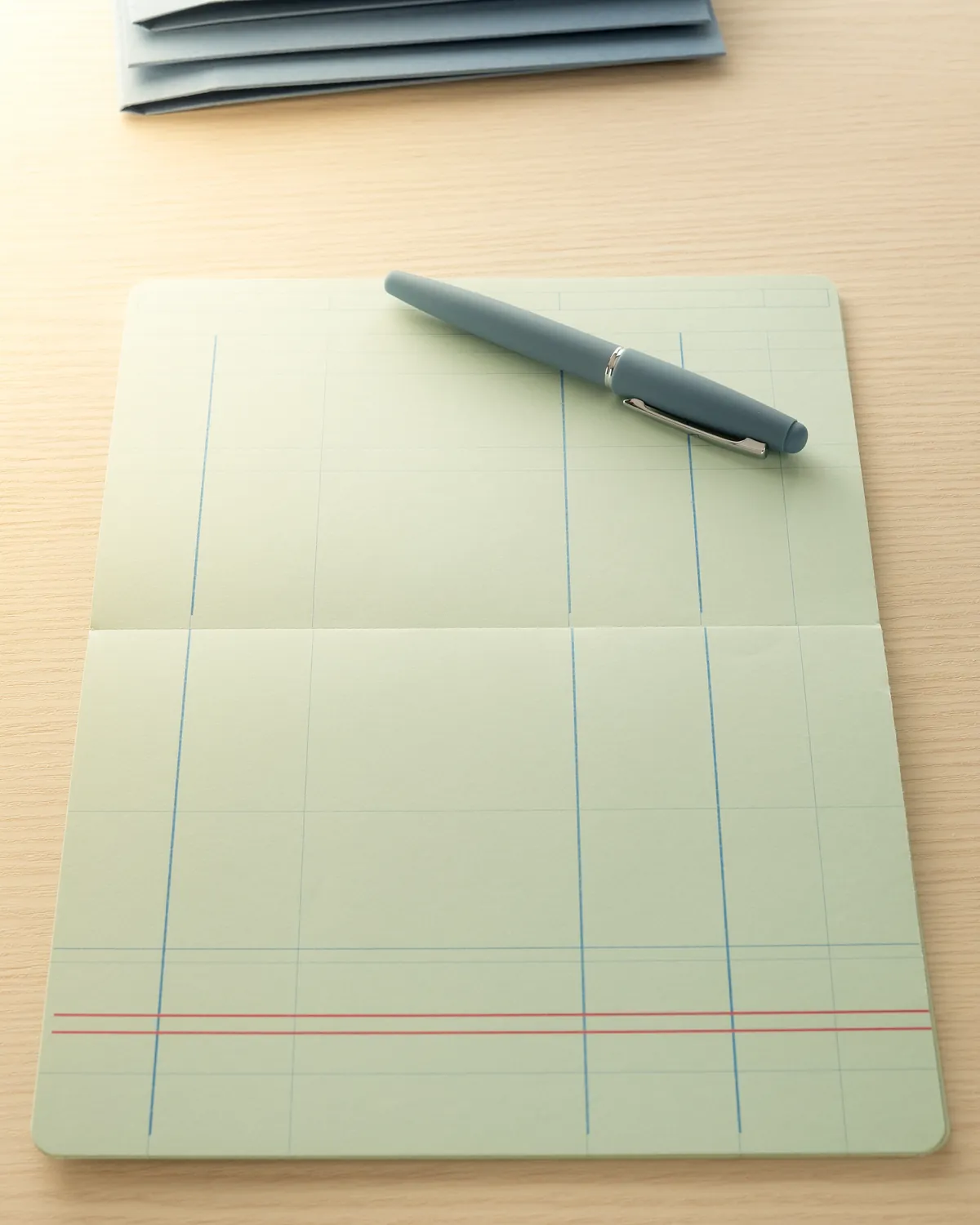 Schreibtisch mit Journalbogen, blauen Ordnern und Füllfederhalter